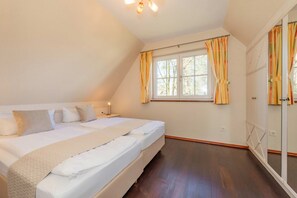 Une chambre à coucher avec un grand lit, une fenêtre avec des rideaux, une armoire et une lampe de chevet.