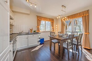 A kitchen with white cabinets, a dining table with chairs, and a window with curtains.