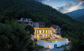 A large, multi-story building with a rooftop garden and multiple balconies, surrounded by dense forest. - Chuxiu Hot Spring Boutique Homestay (Huzhou)