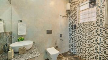 Un baño con un lavamanos blanco, inodoro y zona de ducha.
