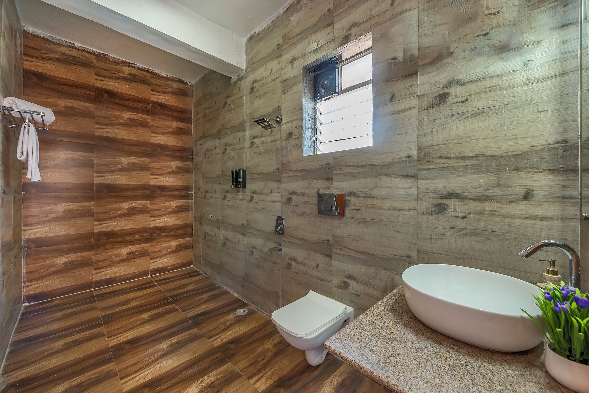 Un baño con pared de madera, un lavamanos blanco y un ventanal pequeño.