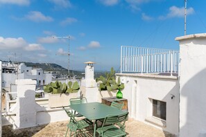 Una terraza en la azotea con una mesa y sillas, una planta de cactus y vistas de la ciudad.