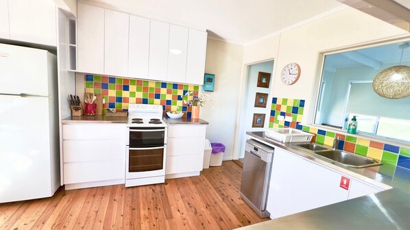 A modern kitchen with white cabinets, a stove, oven, and a dishwasher.