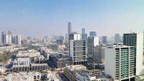 A high-rise building with multiple floors, surrounded by other buildings and construction cranes. - Luxurious Belvilla 1BR JVC with Pool, Gym & BBQ Access (Dubai)