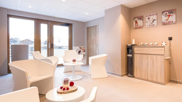 Eine moderne Hotelhalle mit weißen Möbeln, einem Empfangstresen und Wandbildern zum Thema Sport.