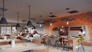 A modern restaurant with high tables, bar stools, and hanging pendant lights.