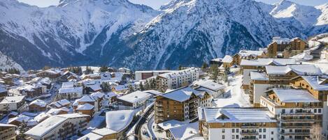 A snow-covered mountain town with wooden buildings and a winding road.