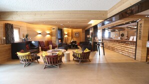A cozy, well-lit reception area with wooden walls and a reception desk. - Chalet in France with Spa & Heated Pool (St Martin de Belleville)
