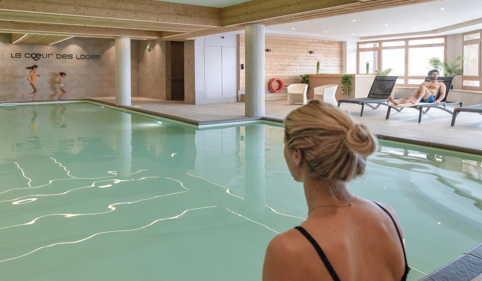 A swimming pool area with a wooden wall and a sign reading "Le coeur des Loges".
