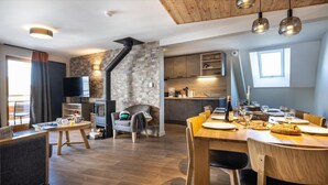 A modern kitchen with a stone backsplash, wooden cabinets, and a dining area with a wooden table and chairs. - Apartment in Risoul with Ski-In/Ski-Out Access (RISOUL)