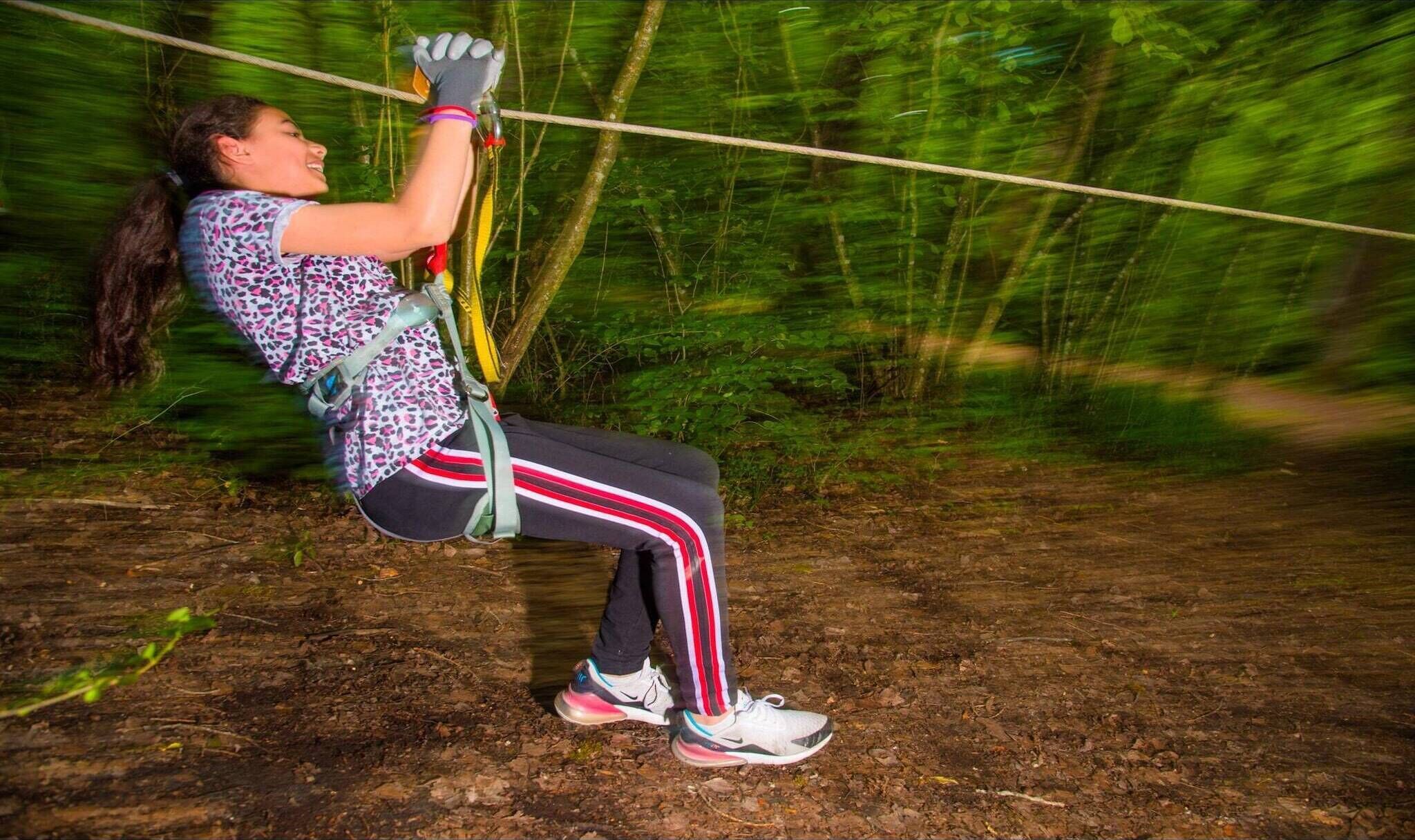 A person zip-lining through a forested area.