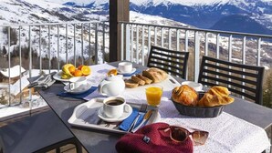 A breakfast setup on a balcony with a mountain view.