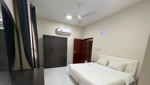 Ein Schlafzimmer mit Bett, Kleiderschrank, Deckenventilator und Klimaanlage.