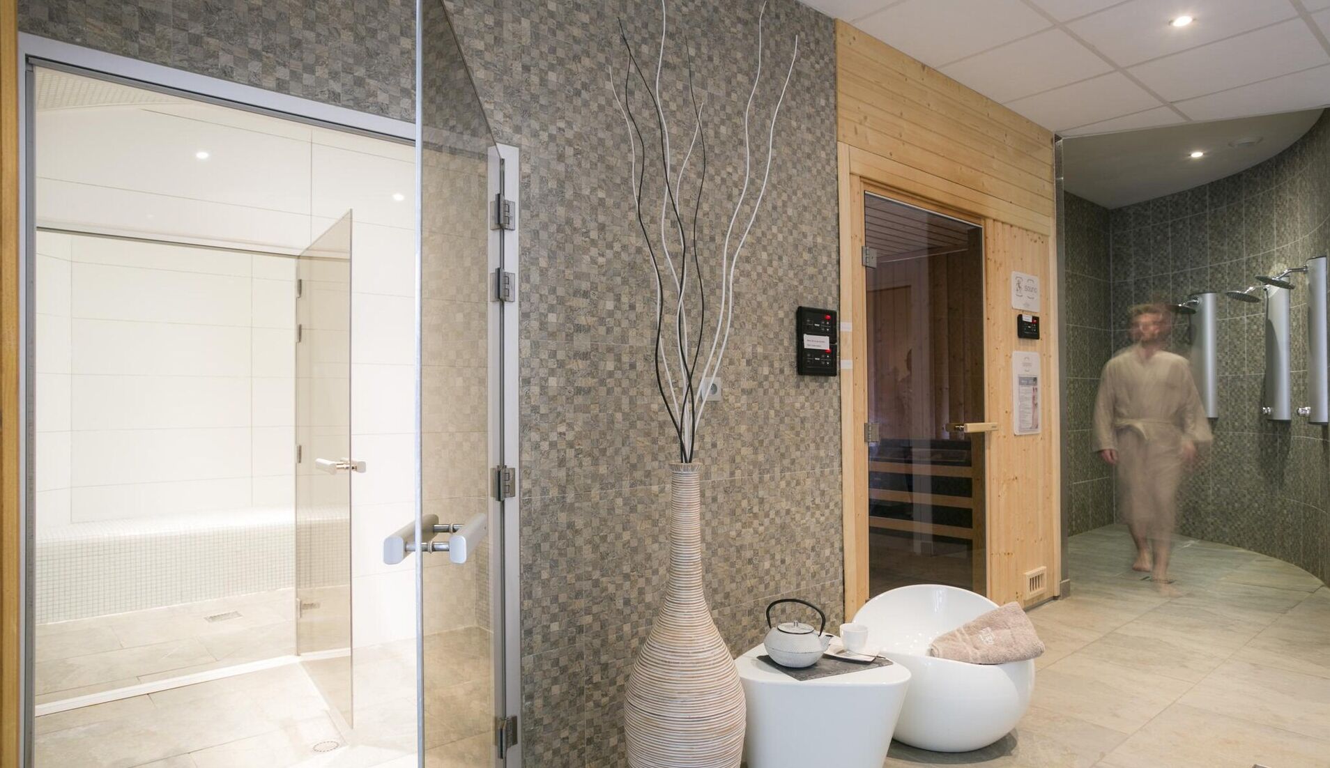 Ein modernes Badezimmer mit einer Duschkabine aus Glas, einer Holztür und einer weißen Badewanne.