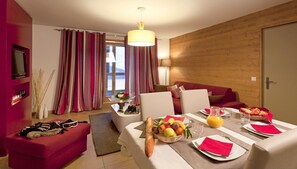 Ein modernes Hotelzimmer mit Essbereich, einer Couch, einem Fernseher und einer Holzwand.