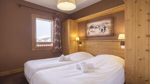 Habitación de hotel con dos camas, ventana con vistas, paneles de madera y un cuadro en la pared.