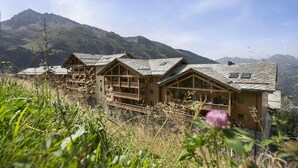A chalet-style hotel with multiple wooden balconies, set against a mountainous backdrop. - Apartment in Sainte-Foy with Ski-In/Ski-Out (Sainte-Foy Tarentaise)