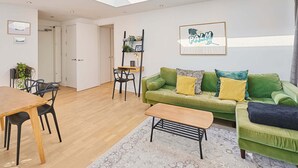 Ein modernes Wohnzimmer mit einem grünen Sofa, einem Holztisch und einem Essbereich mit einem Holztisch und Stühlen.