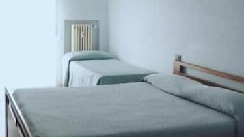 Une chambre avec deux lits, un radiateur et une fenêtre avec des rideaux.