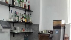A kitchen with a marble countertop, a coffee machine, and shelves with various bottles. - Hotel Mira (Varese)