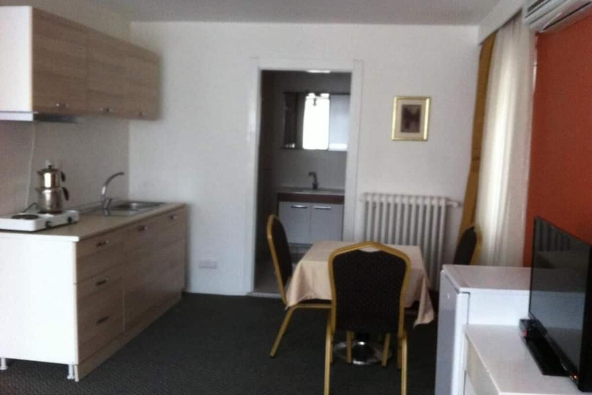 A compact hotel room with a kitchenette, a dining area, and a small bathroom.
