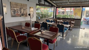 Un restaurant avec des tables et des chaises, un ventilateur et une vue sur la rue.