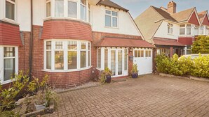 A residential area with houses featuring red brick facades, white window frames, and a paved driveway. - Host Stay The Midland Nest (Birmingham)