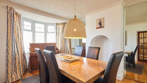 A dining area with a wooden table, black chairs, and a hanging light fixture. - Host Stay The Midland Nest (Birmingham)