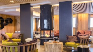 A modern lounge area with a central fireplace, wooden accents, and comfortable seating.