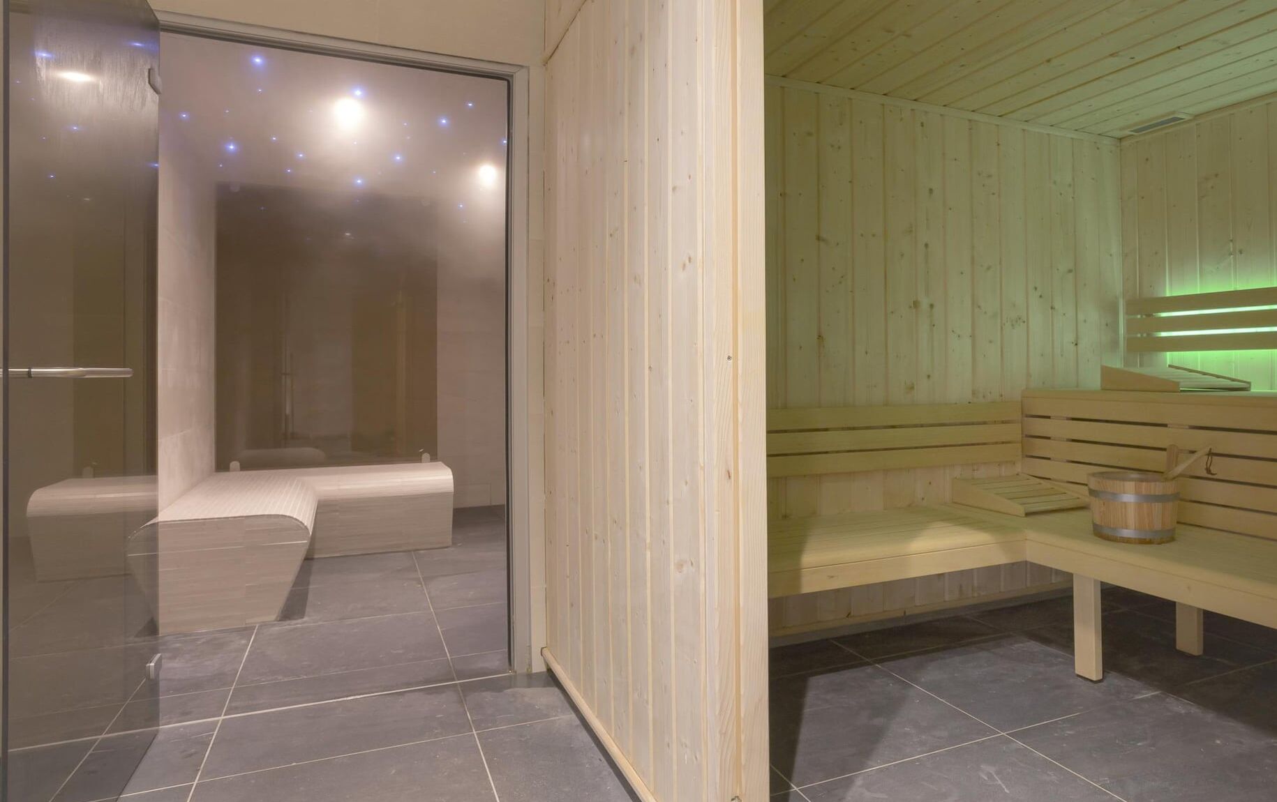 A modern sauna with wooden benches and a glass partition.