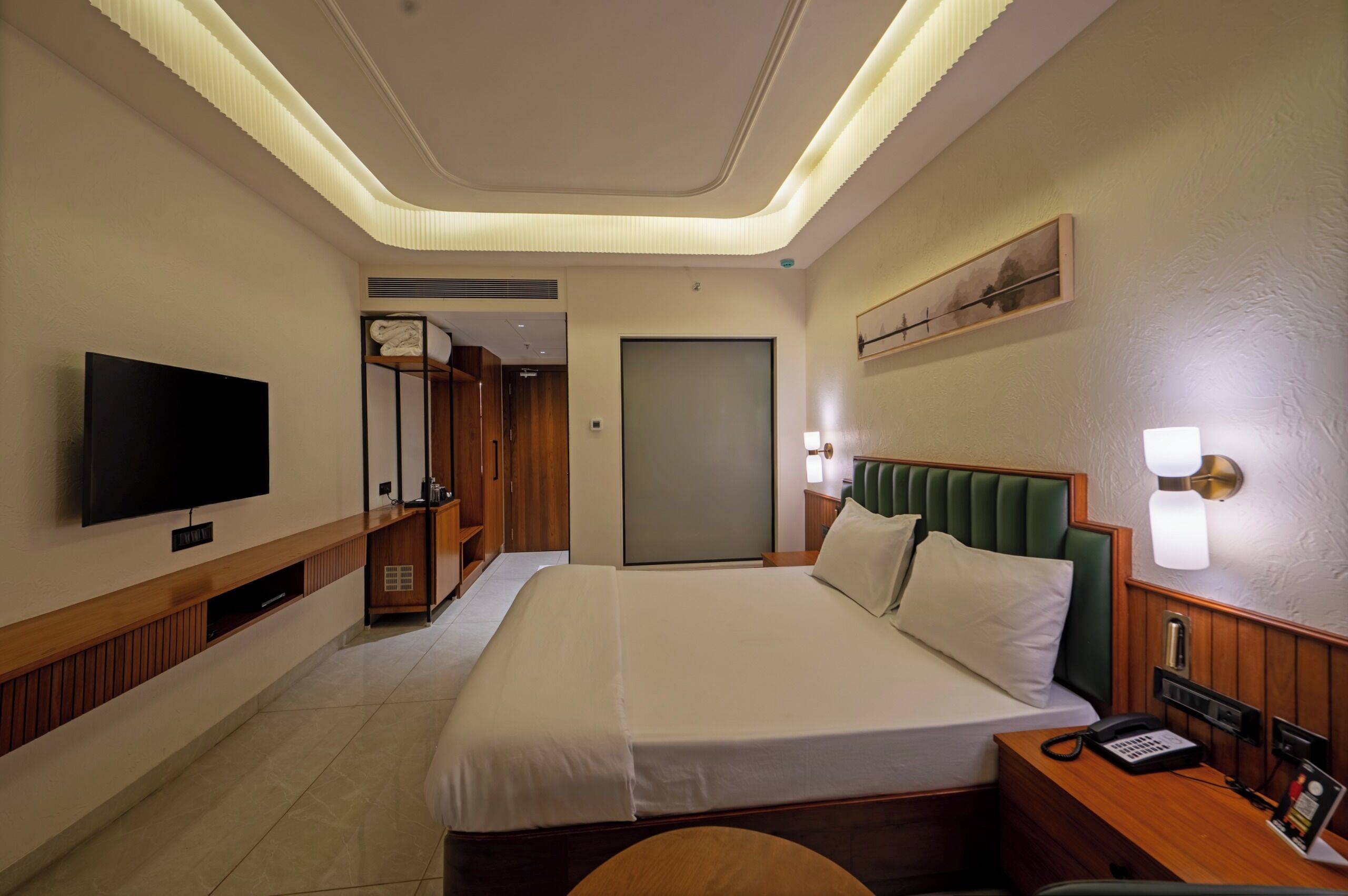 A hotel room with a large bed, a television, a wardrobe, a mirror, and a door.