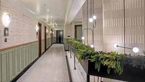 A hotel corridor with a long reception desk, green paneling, and a patterned wall. - Hotel Idyllic Inn (Bhopal)