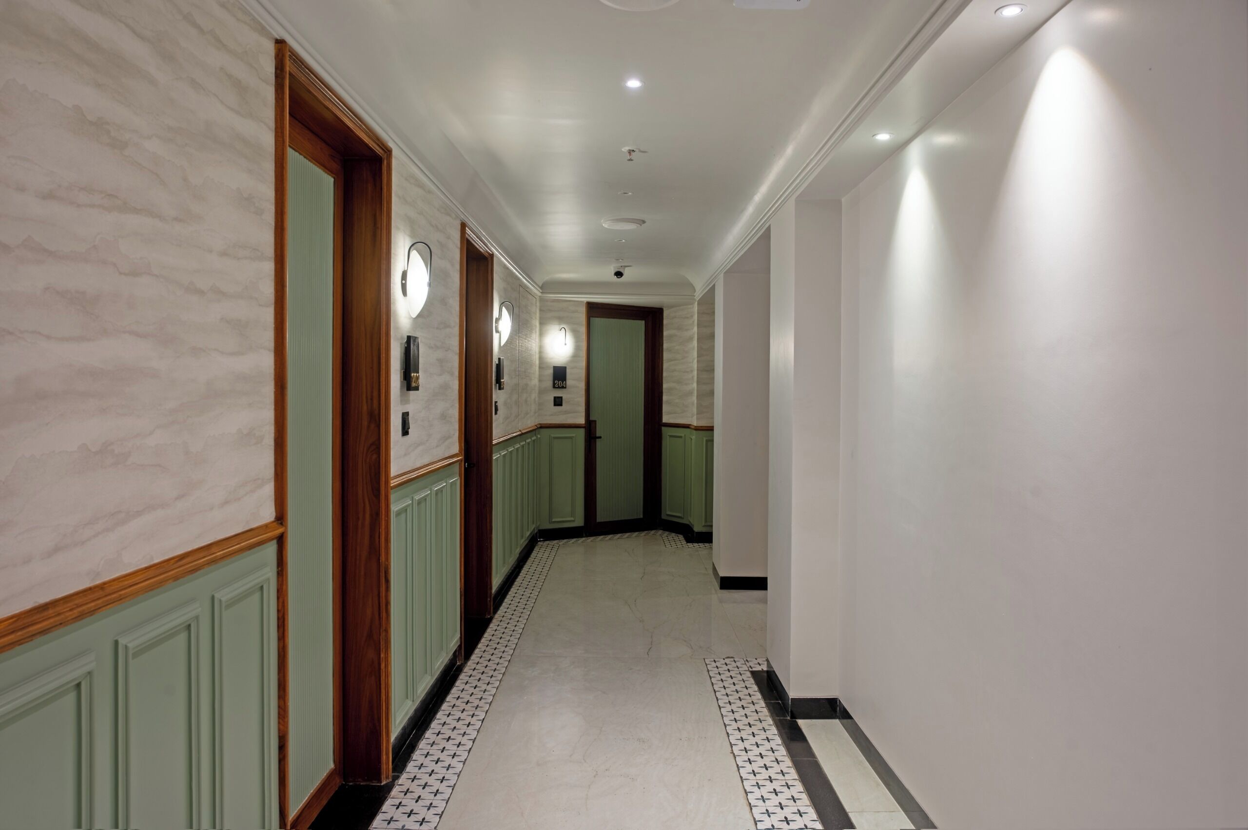 A hallway with a marble wall, green paneling, and a patterned floor.