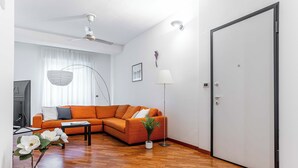 A living room with a sectional sofa, a coffee table, a floor lamp, and a potted plant. - Marvellous 2BR flat near city centre (Milan)
