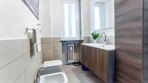 A modern bathroom with a toilet, bidet, sink, and mirror. - Marvellous 2BR flat near city centre (Milan)