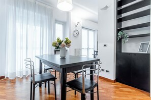 Un comedor moderno con una mesa oscura, sillas negras y un jarrón de flores.