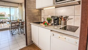 A modern kitchen with white cabinets, a microwave, a coffee maker, and a sink.