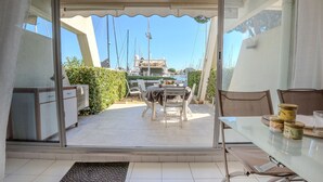 A patio area with a table and chairs, a view of the marina with boats, and a covered seating area.