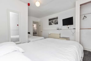 Habitación de hotel con dos camas, un espejo, un televisor y una mesita.