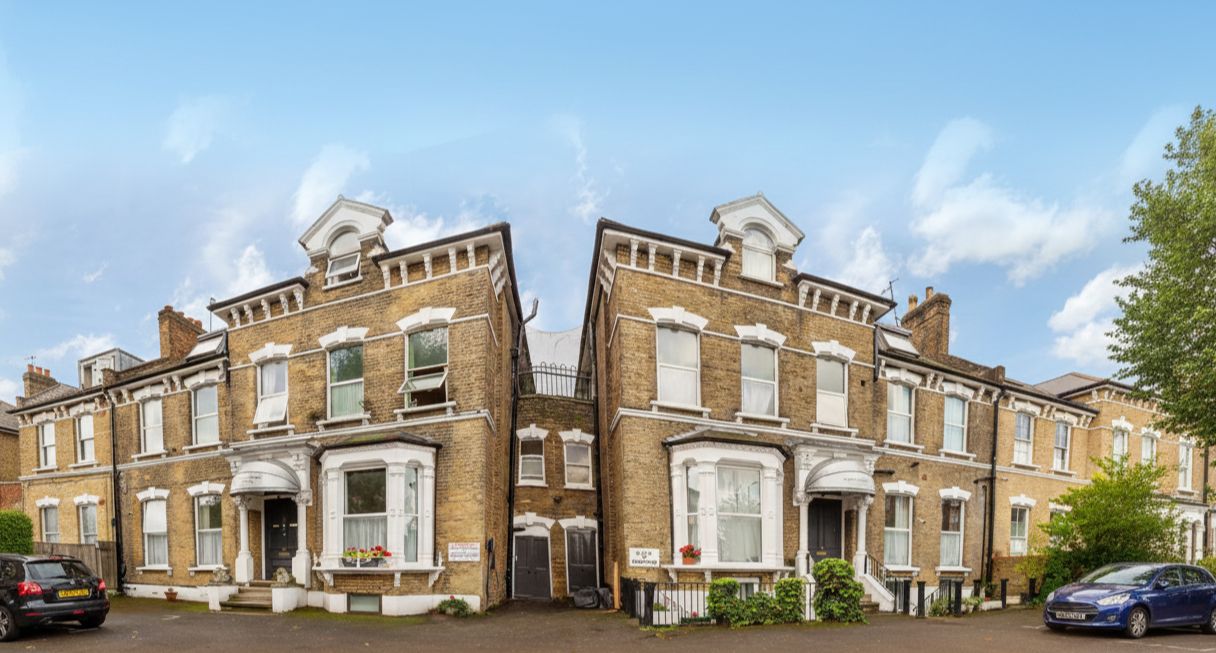 A symmetrical townhouse with a central entrance, large windows, and a brick facade.
