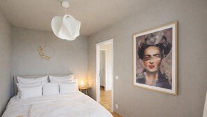 Un dormitorio con una cama, una lámpara de pared y una obra de arte enmarcada.