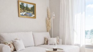 Una sala de estar moderna con un sofá blanco, una mesita redonda y un cuadro en la pared.
