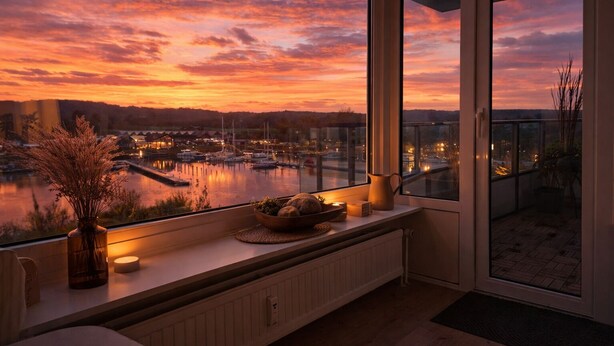Un balcón con vista a un puerto deportivo al atardecer.