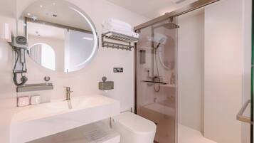 A modern bathroom with a round mirror, a toilet, a glass-enclosed shower, and a towel rack.