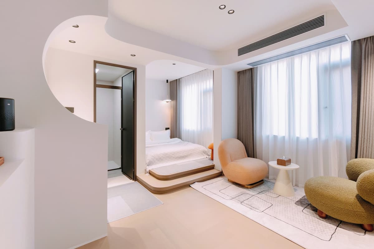 A modern hotel room with a bed, seating area, and a small table.