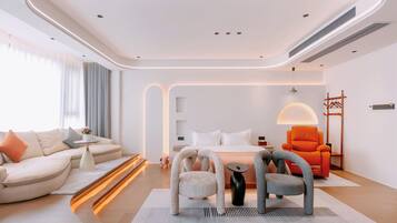A modern hotel room with a curved ceiling, a sofa, a bed, and two chairs.