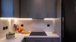 Une cuisine moderne avec des meubles gris, un plan de travail noir et un four encastré.