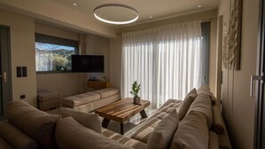 Un salon moderne avec un grand canapé, une table basse et un téléviseur à écran plat fixé au mur.