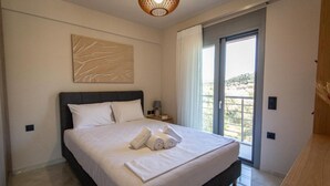Une chambre moderne avec un grand lit, une table de chevet, une œuvre d’art murale et une vue à travers une porte-fenêtre coulissante.