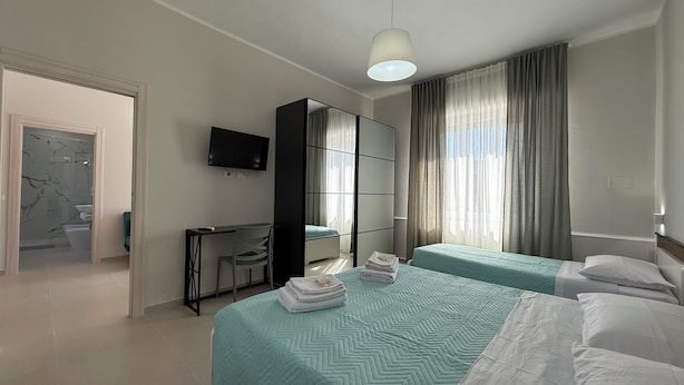 Habitación de hotel con dos camas, un escritorio, un televisor y un armario.